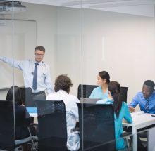 Doctor giving presentation to team of interim doctors at conference room